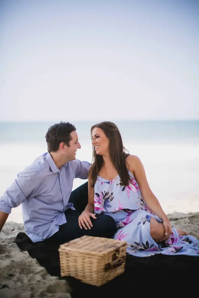 Having a picnic on the beach during their engagement shoot