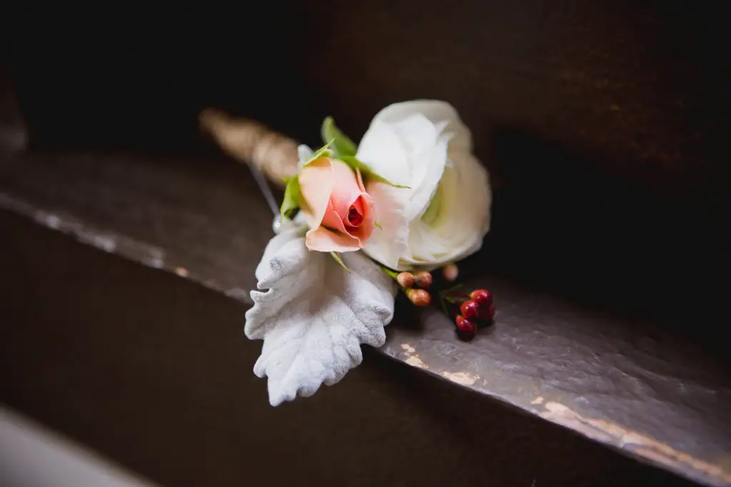 Groom's boutonniere with a white flower and small pink rose wrapped in burlap