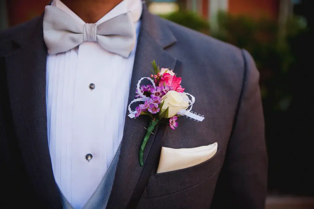 Decorative boutonniere with small purple flowers and a white rose for the groom