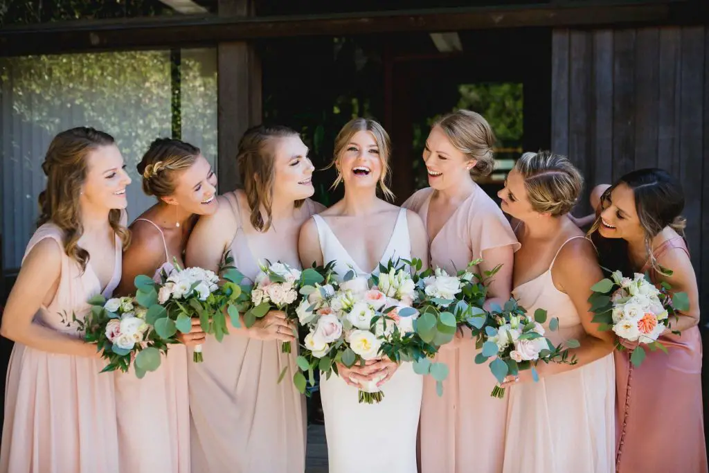 Bridesmaids wearing mismatched blush pink dresses