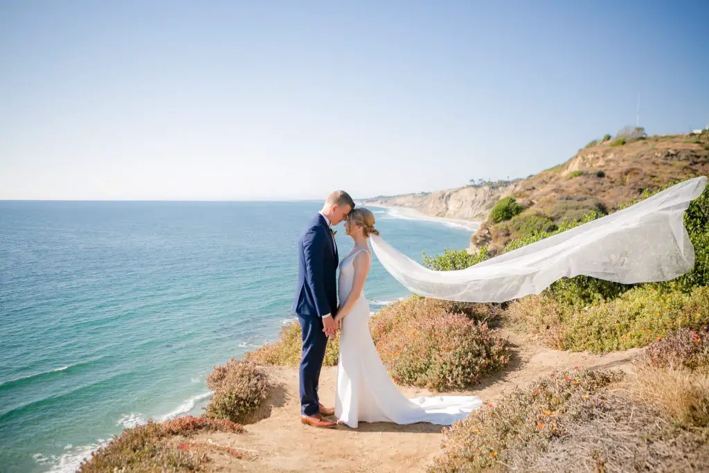 Wedding couple stand on the cliffs by the Martin Johnson House in La Jolla