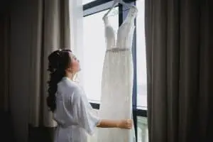 Bride looking at her wedding gown hanging on a hotel window