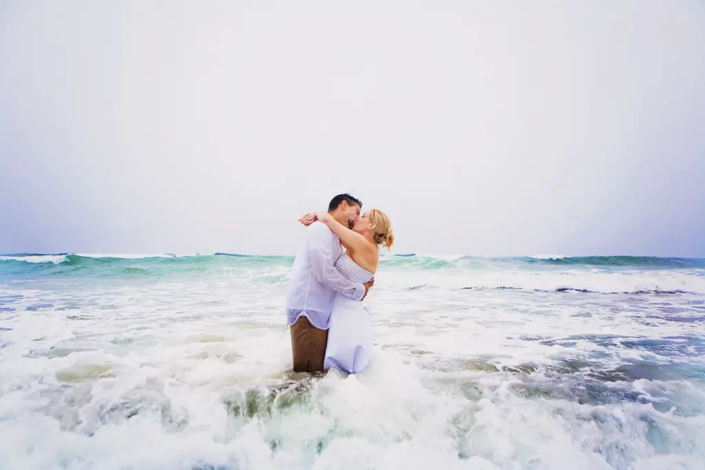 Couple kissing and having their Trash the Dress session on a beach