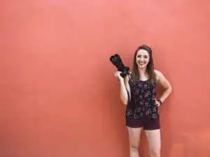 Photographer holding camera in front of red wall