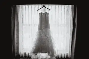 Bride's wedding dress hanging in front of a window